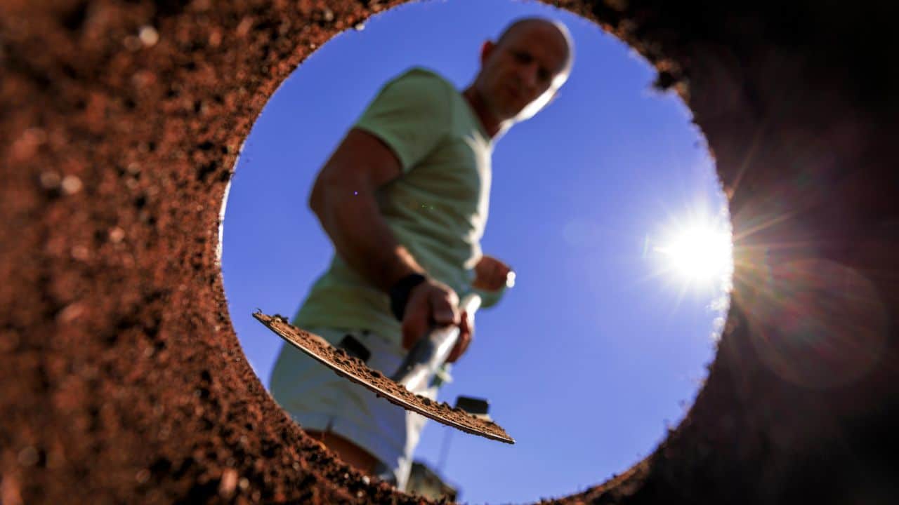 Gardener digging with garden spade in black earth soil. Farming, gardening, agriculture and people concept. Under view man with shovel digging.