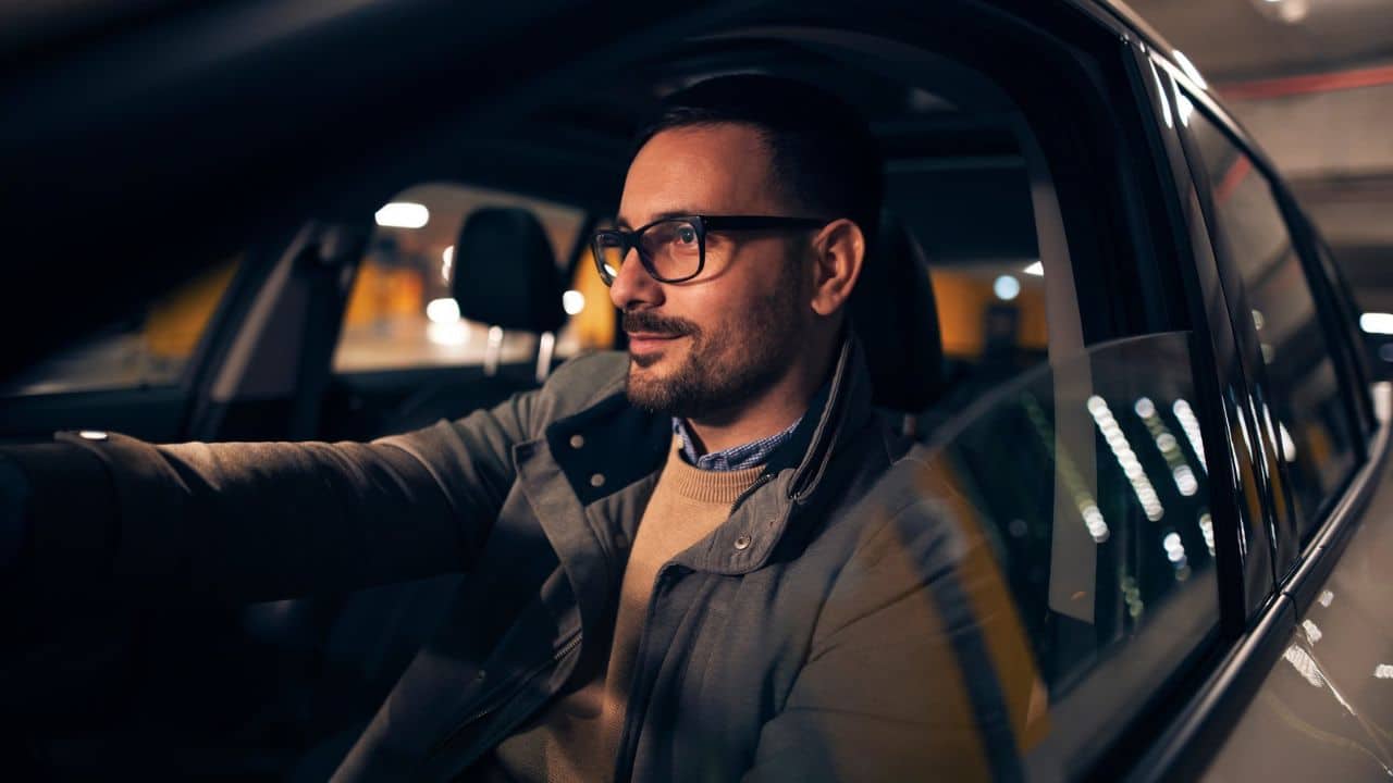 Side view portrait of a handsome stylish man driving car at night