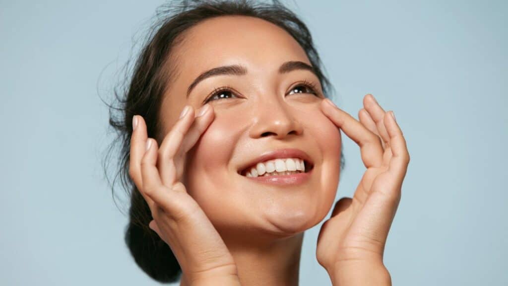 Woman with beauty face touching healthy facial skin portrait. Radiant Skin