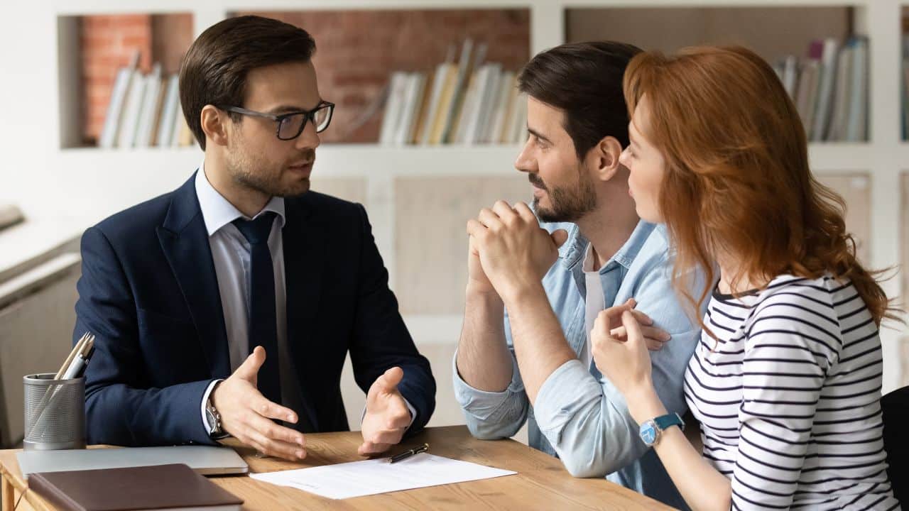 Professional male lawyer financial advisor consulting happy family couple clients in modern office. I