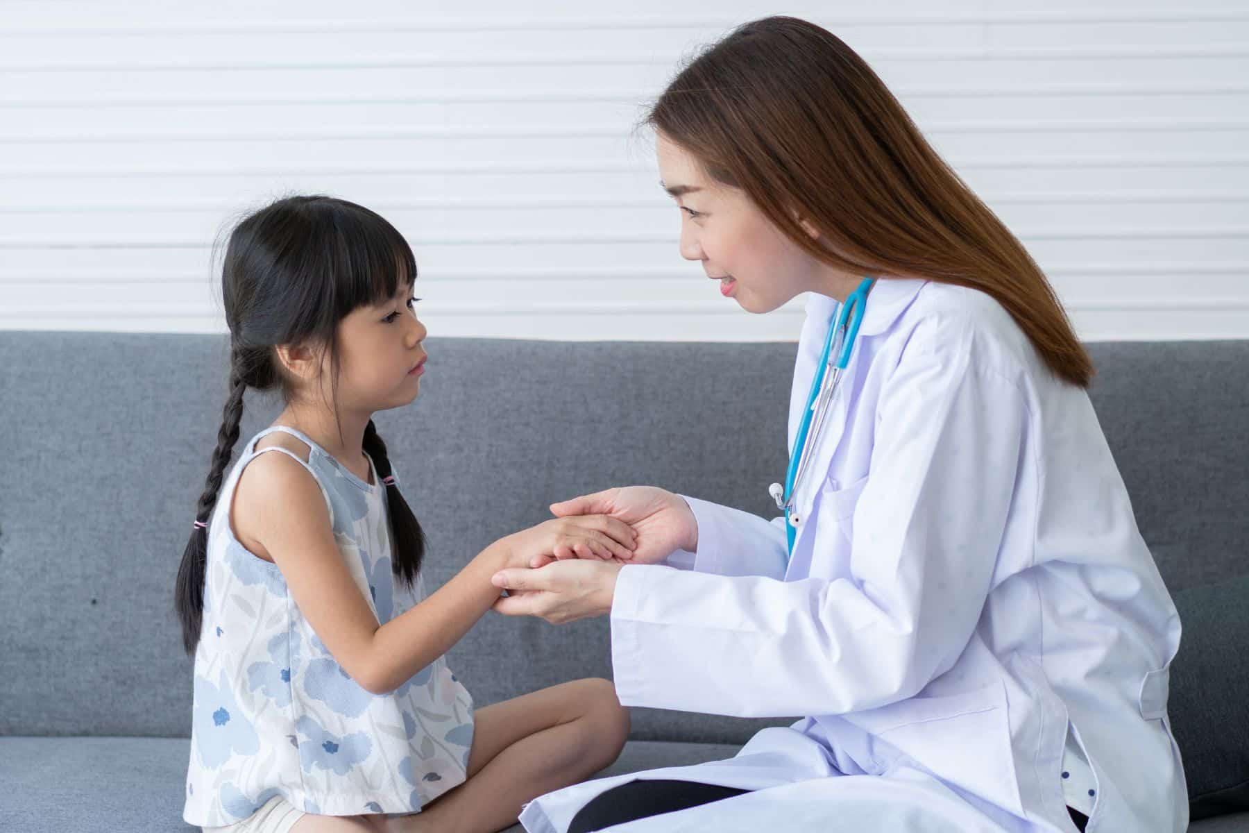 Asian woman pediatrician doctor hold stethoscope for exam a little girl patient and heck heart lungs of kid, Good family doctor visiting child at home, Healthcare and medicine for childhood